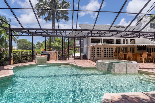 view of swimming pool featuring an in ground hot tub, a patio, an outdoor bar, and a lanai