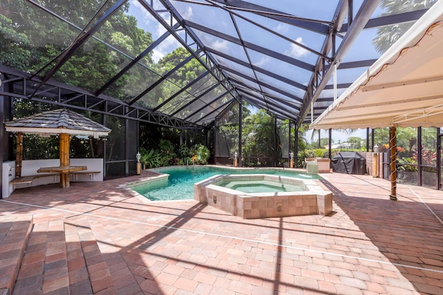 view of pool with an in ground hot tub, a patio, glass enclosure, and grilling area