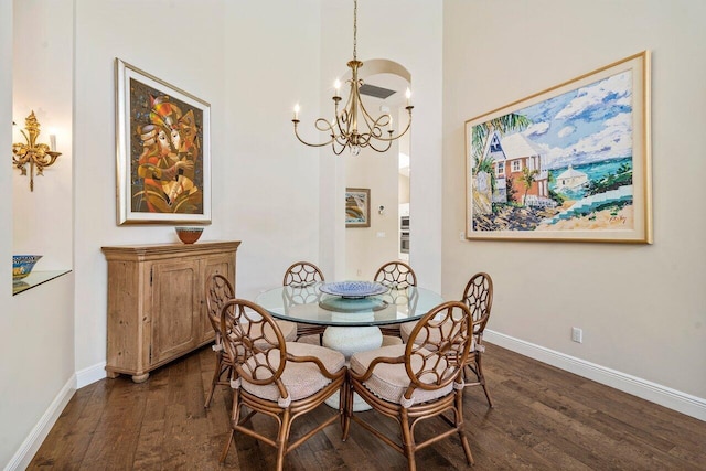 dining area with a high ceiling, a notable chandelier, and dark hardwood / wood-style flooring