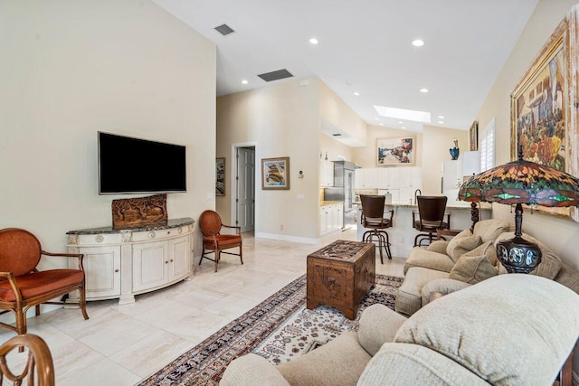 living room with light tile floors, a skylight, and a towering ceiling