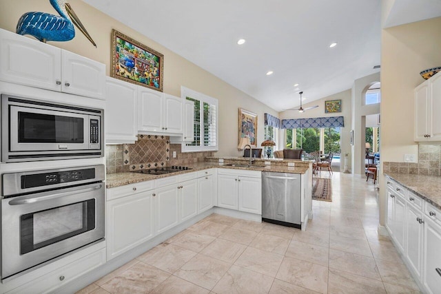 kitchen featuring stainless steel appliances, light stone countertops, kitchen peninsula, white cabinets, and lofted ceiling