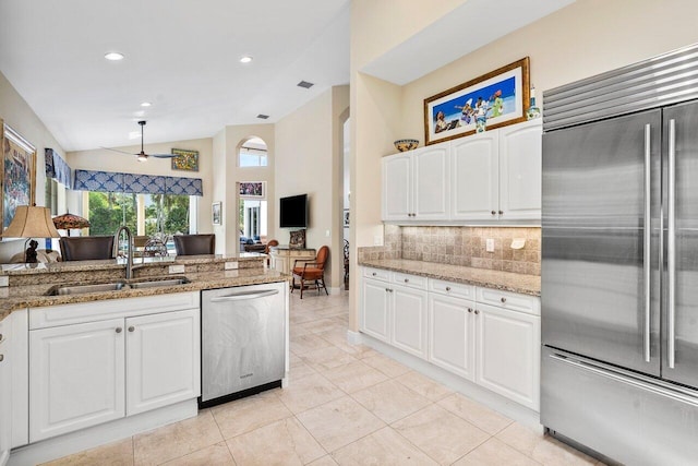 kitchen with light stone countertops, white cabinetry, ceiling fan, sink, and stainless steel appliances