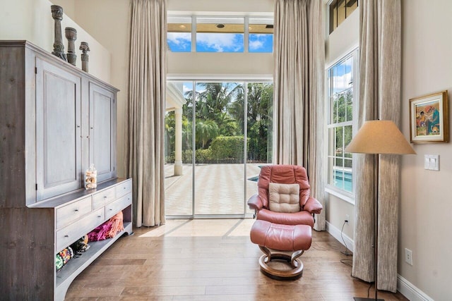 sitting room with a high ceiling, light wood-type flooring, and a wealth of natural light