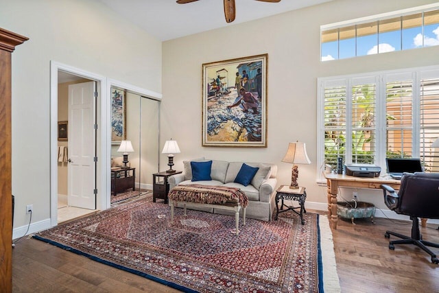 office space with a towering ceiling, ceiling fan, and light hardwood / wood-style flooring