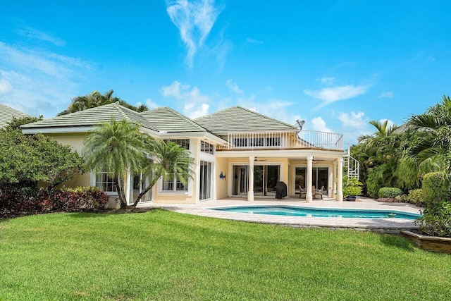 rear view of property with a yard, a balcony, and a patio