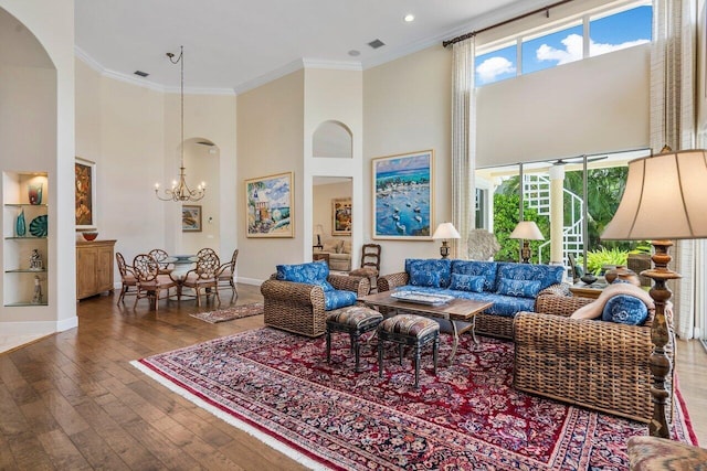 living room with a towering ceiling, a notable chandelier, dark hardwood / wood-style floors, and crown molding