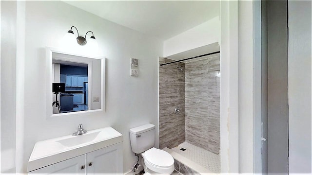 bathroom with vanity, tiled shower, and toilet