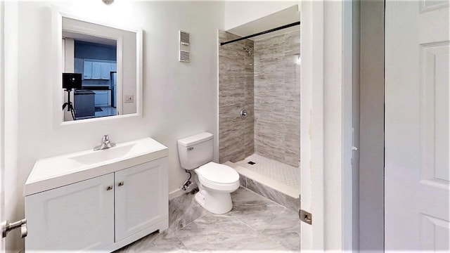 bathroom with vanity, toilet, and a tile shower