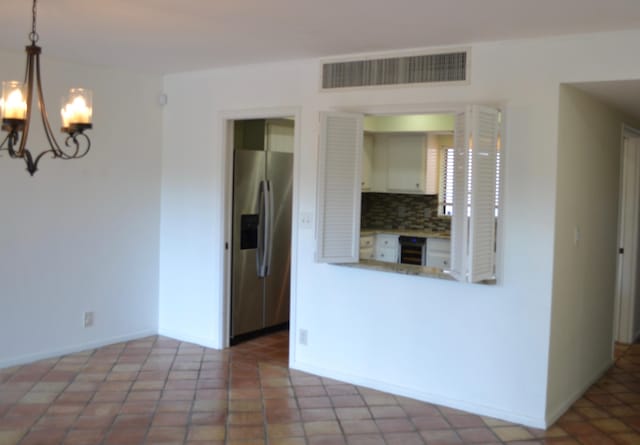 unfurnished room with a notable chandelier and wine cooler