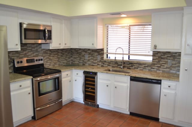 kitchen featuring tasteful backsplash, wine cooler, appliances with stainless steel finishes, sink, and white cabinets