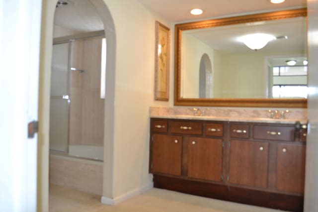 bathroom with bath / shower combo with glass door and vanity