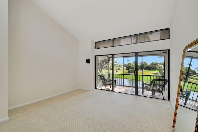 unfurnished room featuring high vaulted ceiling, a water view, and light colored carpet