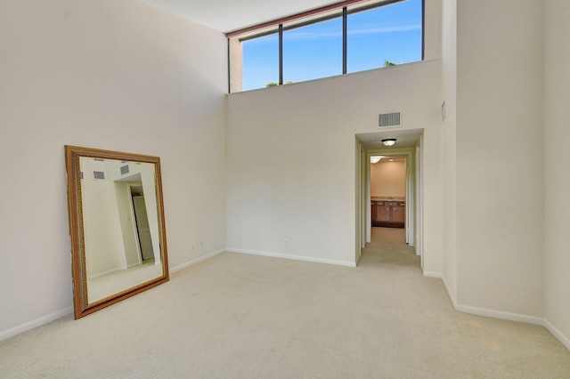 carpeted spare room with a towering ceiling