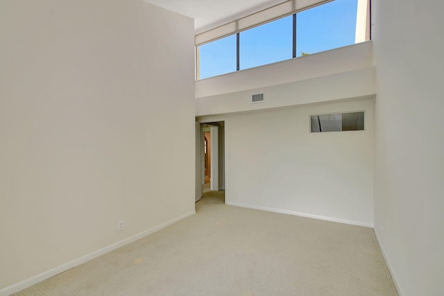 carpeted spare room featuring a towering ceiling