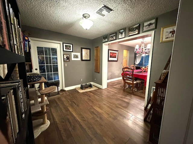 interior space featuring a notable chandelier, a textured ceiling, and dark hardwood / wood-style floors