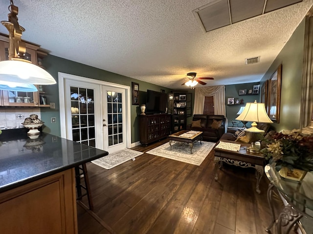 living room featuring dark hardwood / wood-style floors, a textured ceiling, ceiling fan, and french doors