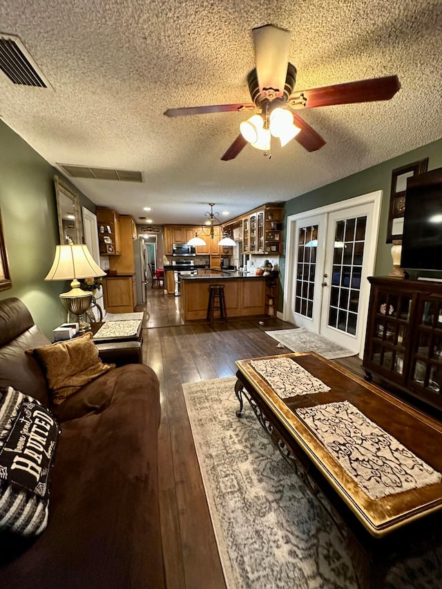 living room featuring french doors, dark hardwood / wood-style flooring, a textured ceiling, and ceiling fan