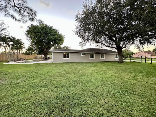 back of house featuring a fenced in pool, a lawn, and a patio