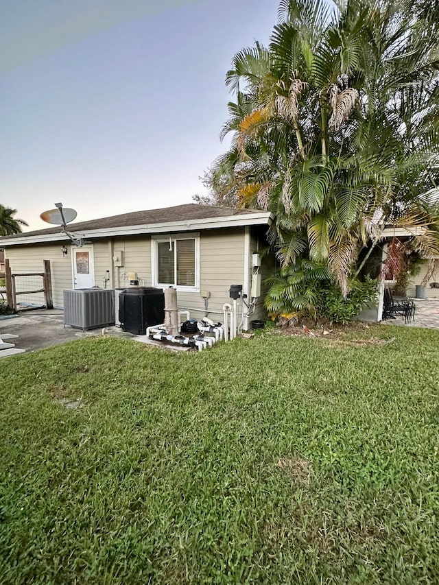 rear view of house featuring a lawn, a patio area, and central AC