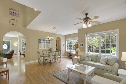 living room with ceiling fan with notable chandelier and light hardwood / wood-style flooring