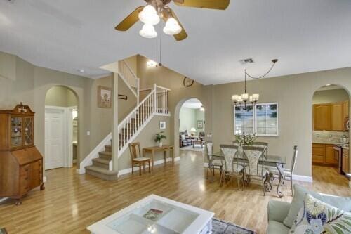 living room with light wood-type flooring and ceiling fan with notable chandelier