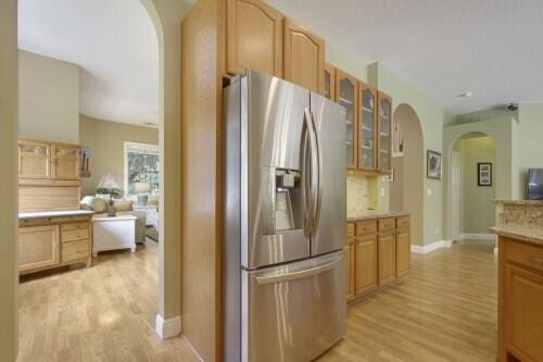 kitchen featuring stainless steel fridge, light wood-type flooring, and light brown cabinetry