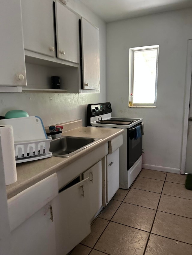 kitchen featuring light tile floors, white range with electric cooktop, white cabinetry, and sink