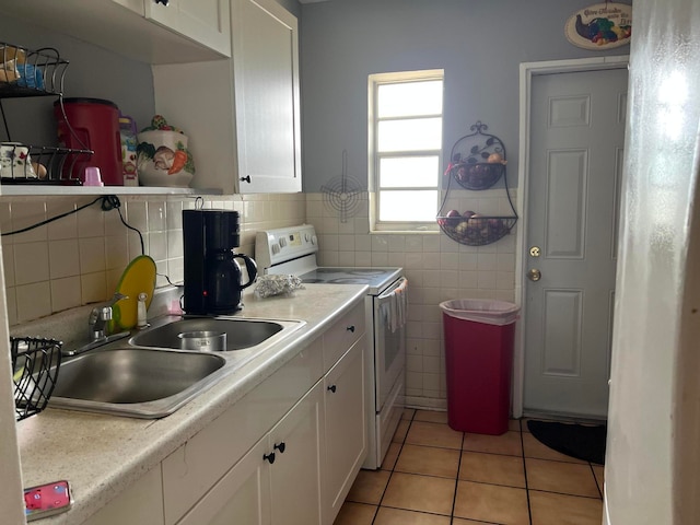 kitchen featuring white electric range, light tile floors, white cabinets, backsplash, and sink