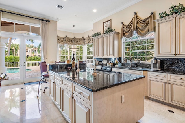 kitchen featuring dark stone countertops, a kitchen island, decorative backsplash, and a healthy amount of sunlight