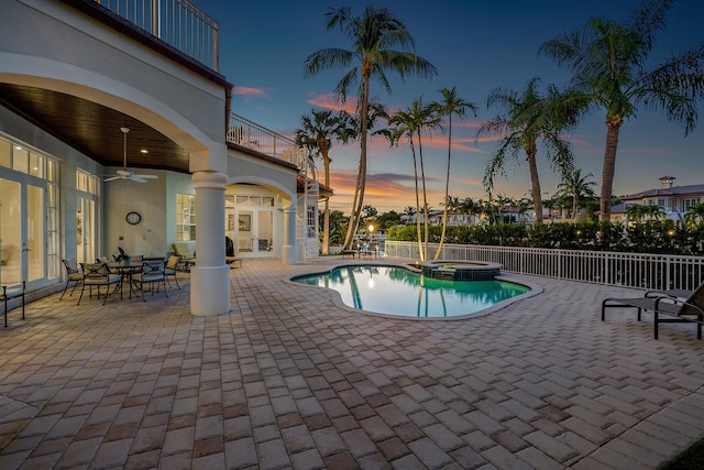 pool at dusk featuring an in ground hot tub, ceiling fan, and a patio area