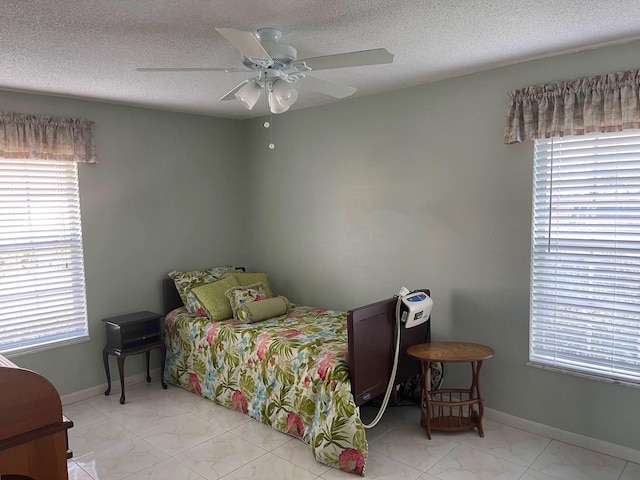 bedroom featuring ceiling fan, light tile floors, and a textured ceiling