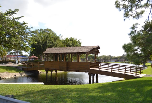 view of dock featuring a lawn and a water view