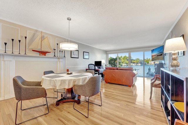 dining room with crown molding, a textured ceiling, and light wood-type flooring