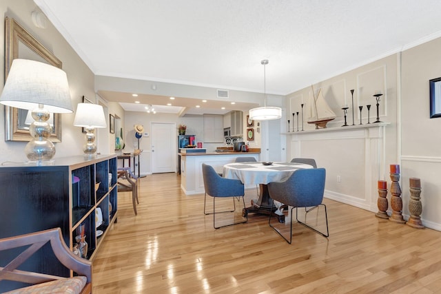 dining space with crown molding and light hardwood / wood-style floors