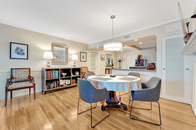 dining space with crown molding, light hardwood / wood-style flooring, and a textured ceiling