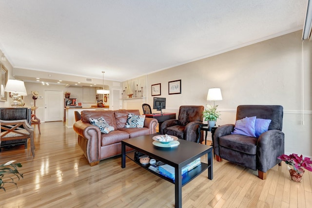 living room with ornamental molding and light hardwood / wood-style flooring