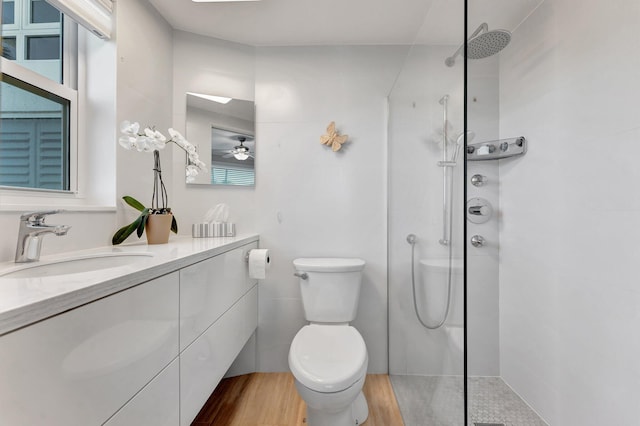 bathroom featuring a tile shower, tile walls, hardwood / wood-style flooring, vanity, and toilet