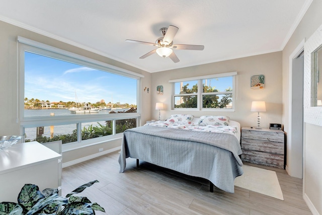 bedroom featuring ceiling fan, ornamental molding, multiple windows, and light hardwood / wood-style flooring