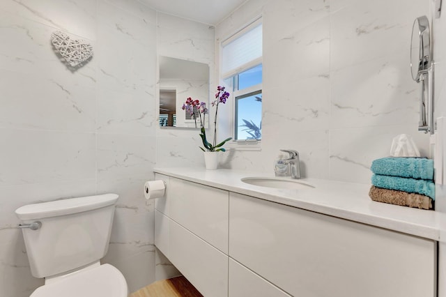 bathroom featuring vanity, toilet, and tile walls