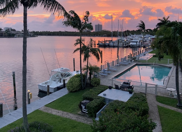 view of dock with a water view, a community pool, a patio, and a lawn