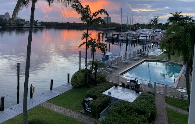 view of dock with a water view and a community pool