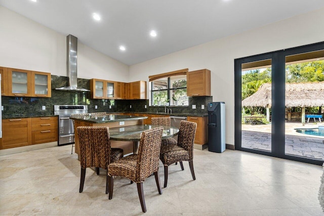 interior space with light tile floors, stove, wall chimney range hood, tasteful backsplash, and a center island