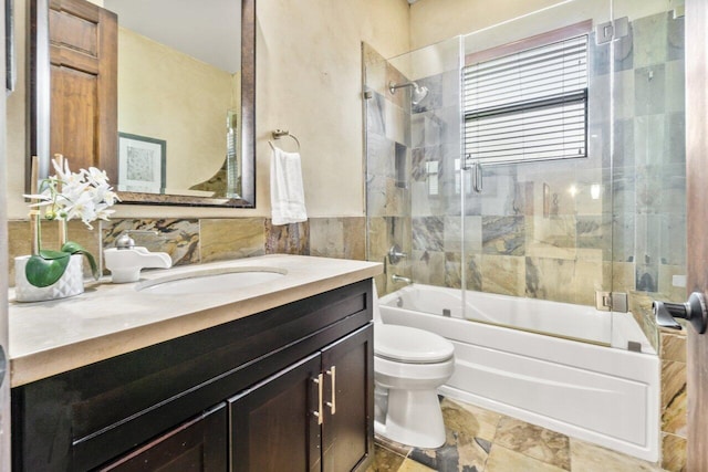 full bathroom featuring vanity, tile walls, tile flooring, toilet, and shower / bath combination with glass door