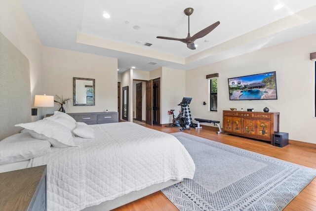 bedroom featuring a tray ceiling, ceiling fan, and light hardwood / wood-style flooring