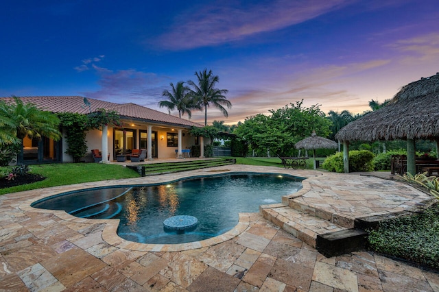 pool at dusk with a gazebo, a lawn, and a patio area