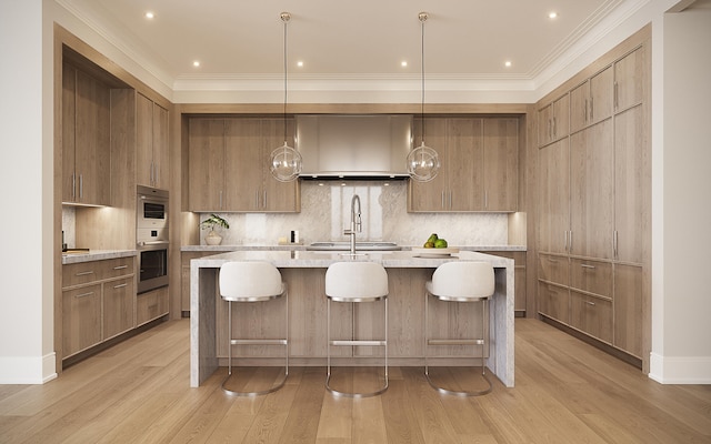 kitchen with backsplash, an island with sink, decorative light fixtures, and light wood-type flooring