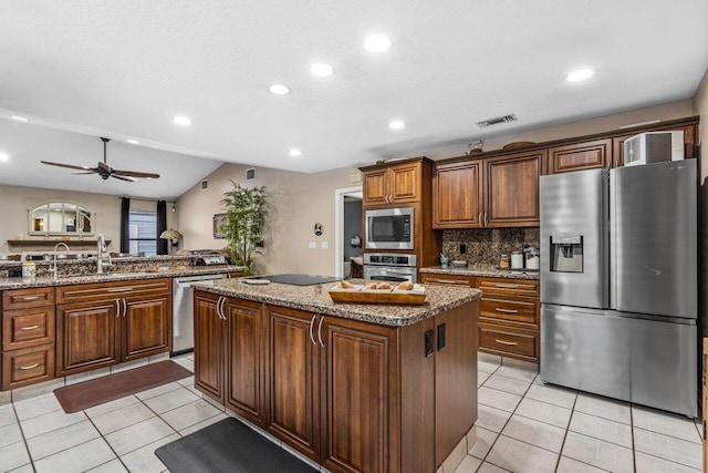 kitchen featuring stainless steel appliances, a kitchen island, ceiling fan, tasteful backsplash, and sink