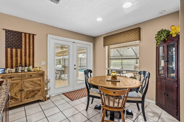 tiled dining room featuring a textured ceiling and french doors