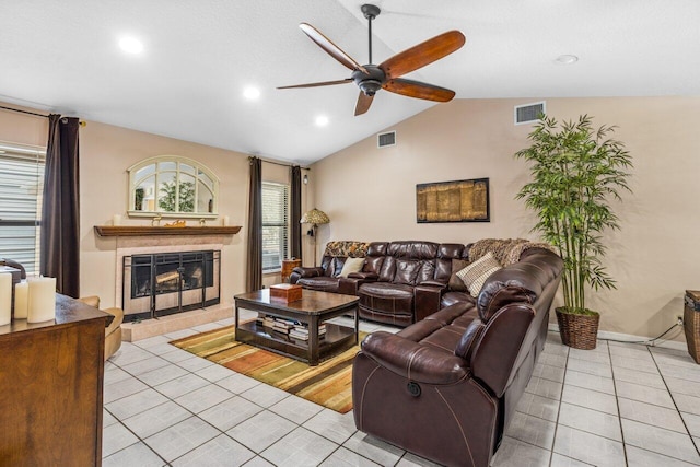 tiled living room with a tiled fireplace, ceiling fan, and vaulted ceiling