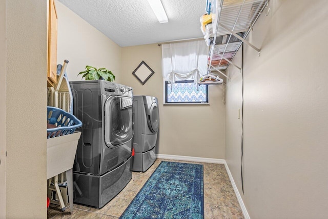 laundry area featuring light tile floors, a textured ceiling, and independent washer and dryer